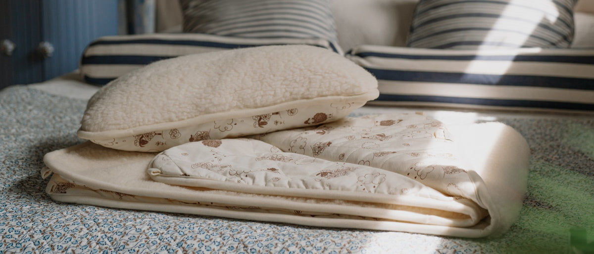 Gefaltetes Wollunterbett und Kopfkissen auf einem Bett