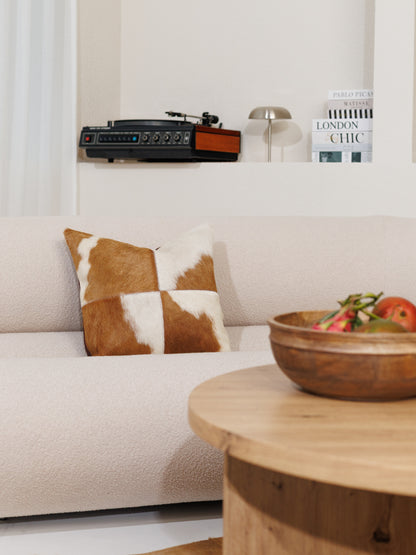 Kuhfell-Kissenbezug in Braun-Weiß auf einem hellen Sofa