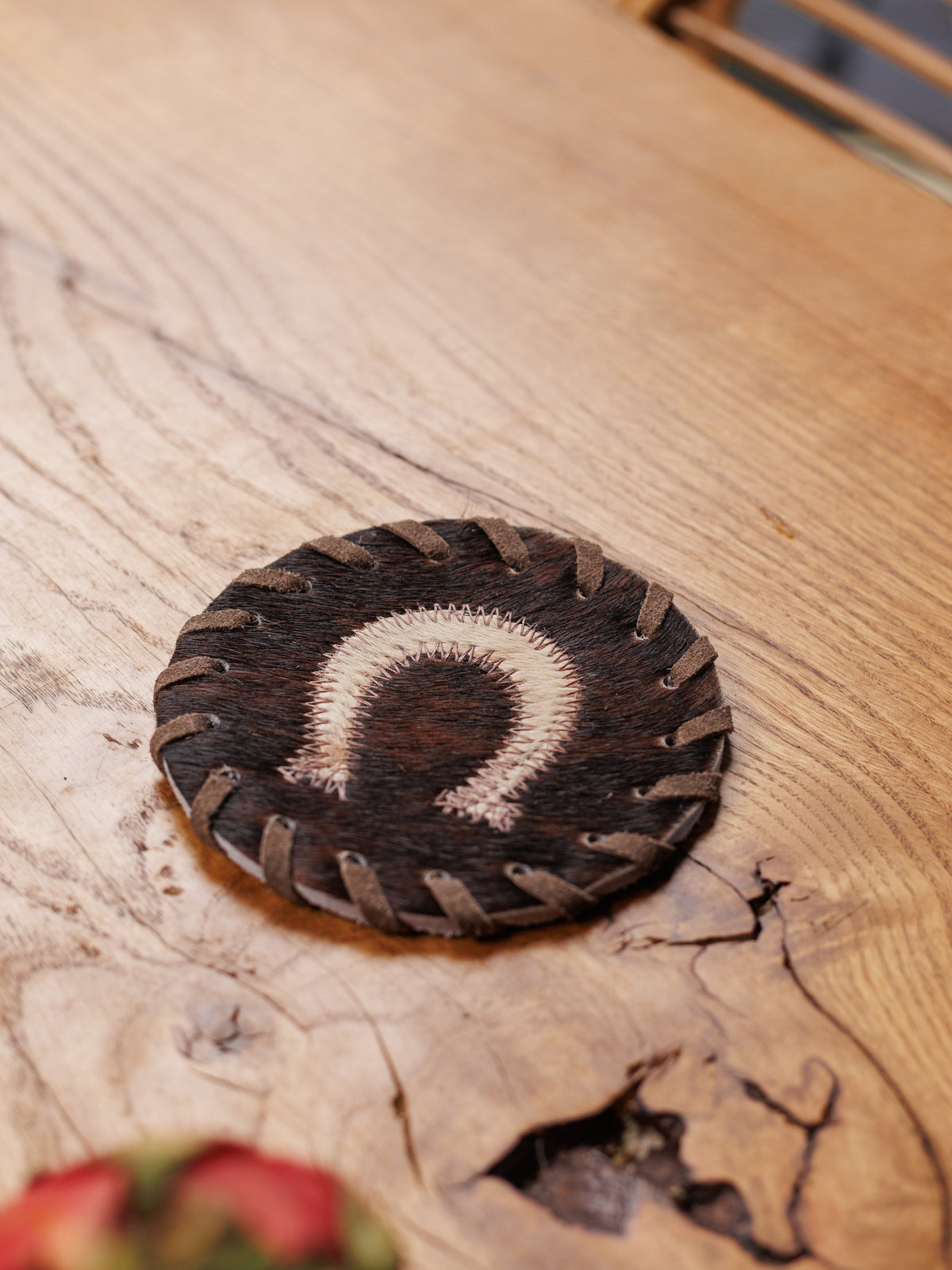 Kuhfell-Untersetzer mit Hufeisen auf einem Holztisch, aus der Nähe